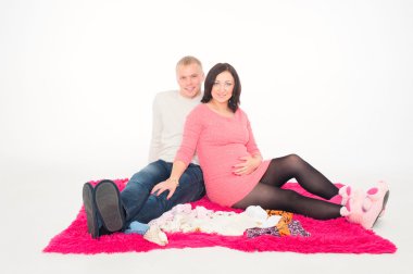 gelecekteki çocuklarının elbiselere bakarak kocasıyla mutlu hamile kadın