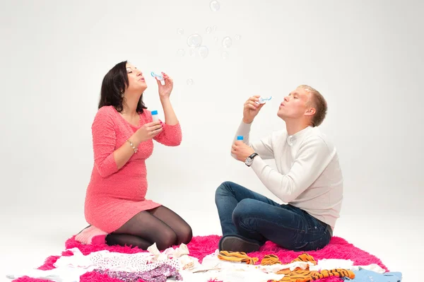 Gelukkig mooie zwangere vrouw en haar echtgenoot zeepbellen blazen — Stockfoto