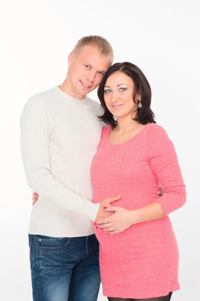 Happy pregnant woman with her husband looking at clothes for their future child — Stock Photo, Image