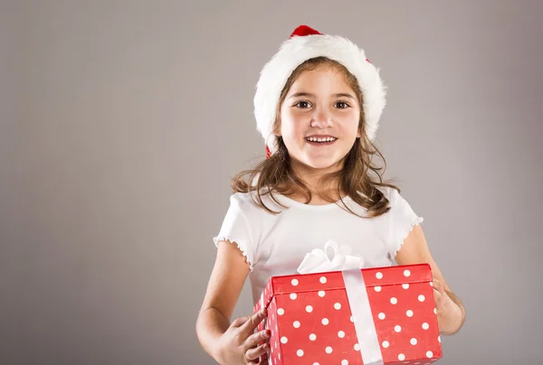 Small girl in santa hat with christmas gift — Stock Photo, Image