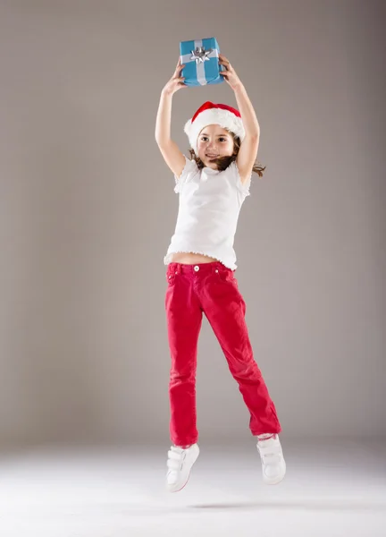 Small girl in santa hat with christmas gift — Stock Photo, Image