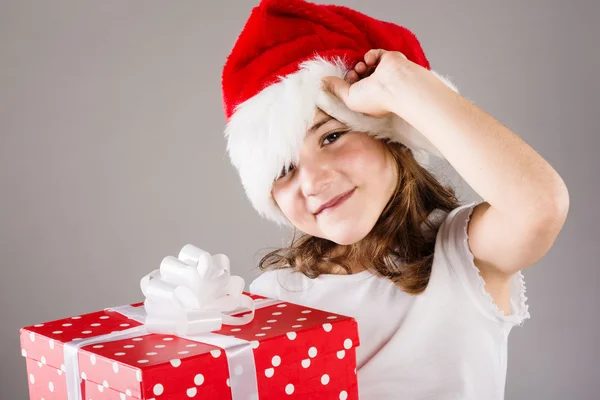 Μικρό κορίτσι σε το καπέλο santa με χριστουγεννιάτικο δώρο — Φωτογραφία Αρχείου