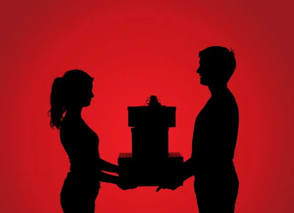 Silhouettes of couple with gift — Stock Photo, Image