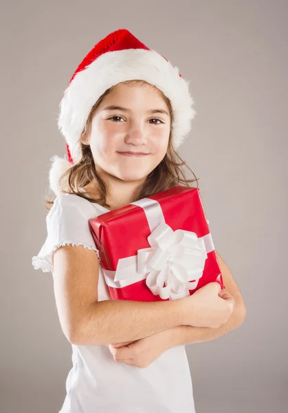 Μικρό κορίτσι σε το καπέλο santa με χριστουγεννιάτικο δώρο — Φωτογραφία Αρχείου