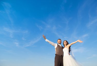 Yeni evli çift dikey, mavi gökyüzü