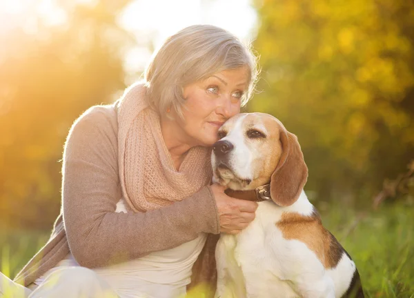 Active senior woman hugs dog — Stock Photo, Image