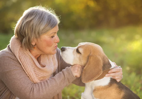 Active senior woman hugs dog — Stock Photo, Image