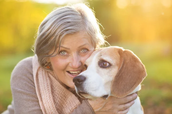 Active senior woman hugs dog — Stock Photo, Image