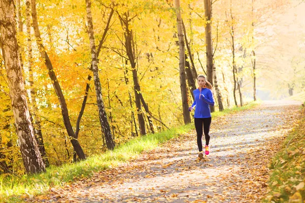 Active and sporty woman runner in autumn nature — Stock Photo, Image