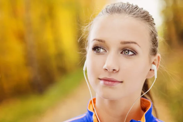 Sporty woman runner listens to music in nature — Stock Photo, Image