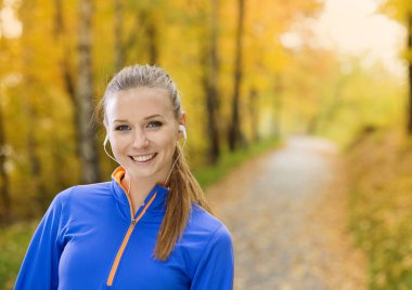 Sporty woman runner listens to music in nature