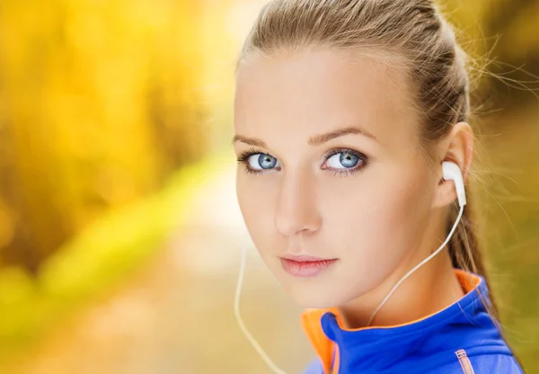 Sporty woman runner listens to music in nature — Stock Photo, Image