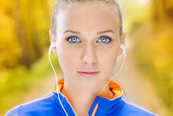 Sportieve vrouw loper luistert naar muziek in de natuur — Stockfoto
