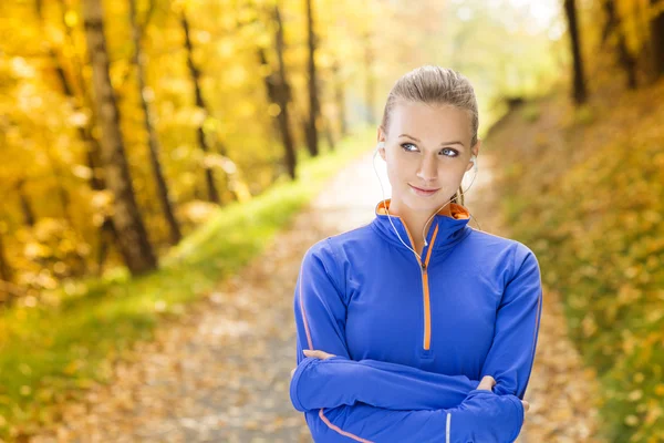 Sporty woman runner listens to music in nature — Stock Photo, Image