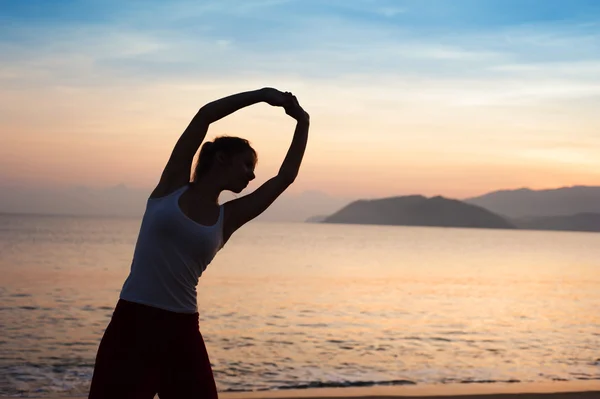 Woman stretching on beach — Stock Photo, Image