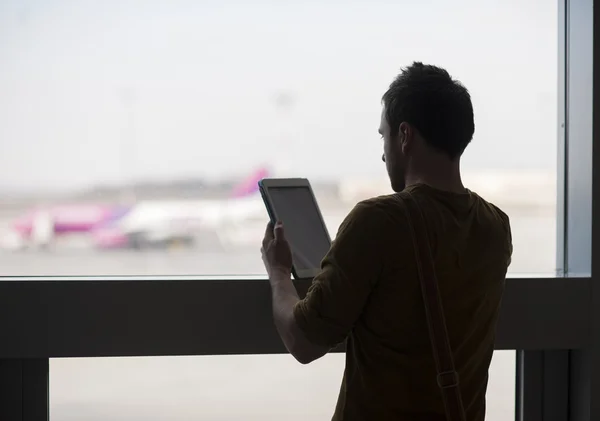 Jonge man met behulp van een tablet op luchthaven — Stockfoto