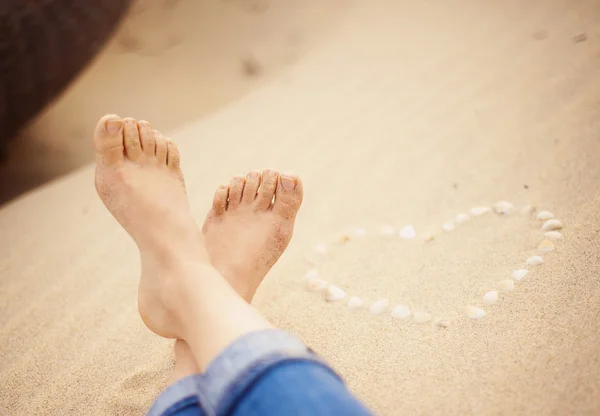 Närbild av kvinnliga fötter på stranden — Stockfoto