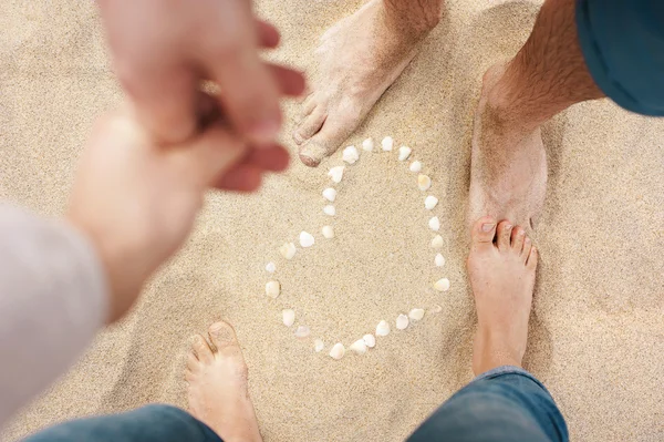 Close-up van mannelijke en vrouwelijke voeten op het strand — Stockfoto