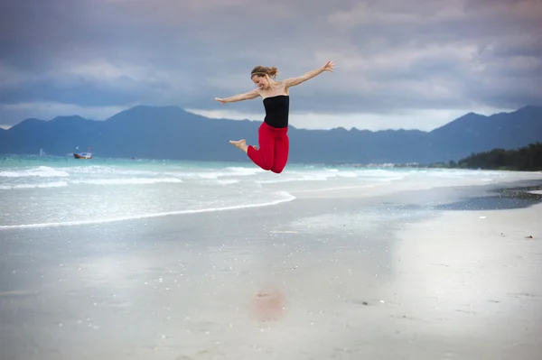 Frau springt am Strand. — Stockfoto