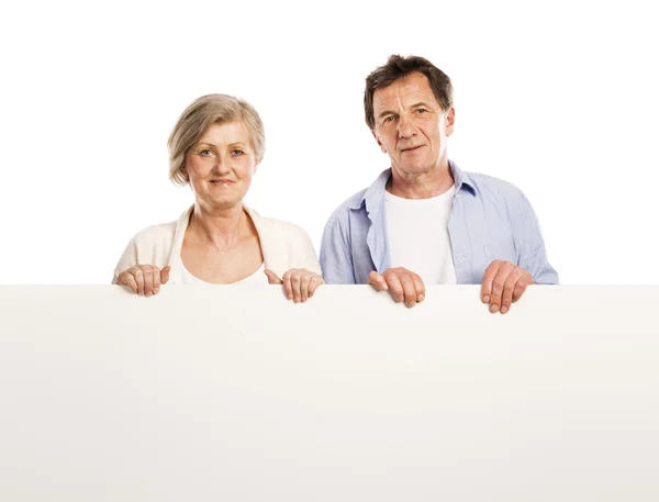 Senior couple with advertising board — Stock Photo, Image