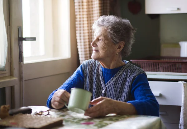 Oude vrouw in de keuken — Stockfoto