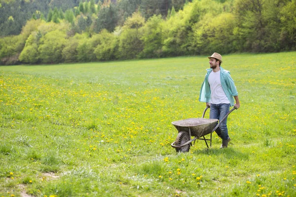 Boer met kruiwagen in veld — Stockfoto