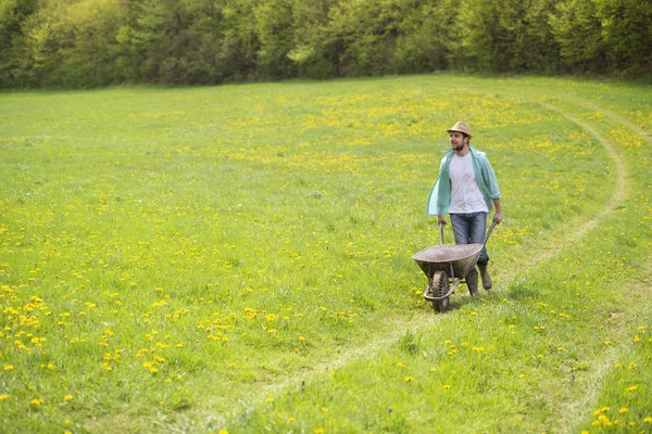 Boer met kruiwagen in veld — Stockfoto