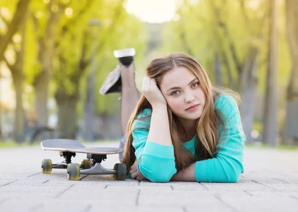 Flicka med skateboard liggande i gränd — Stockfoto