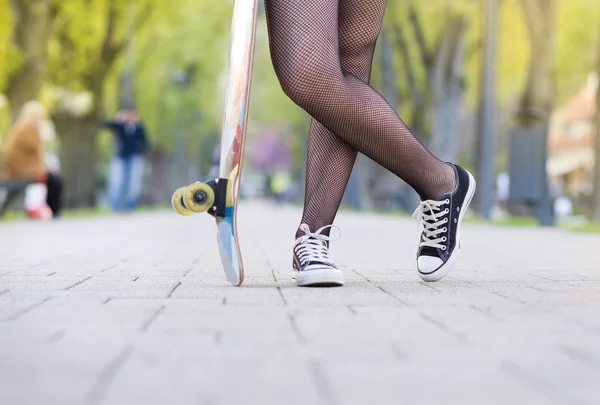 Pernas de menina segurando skate — Fotografia de Stock