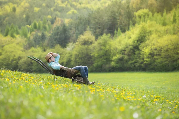 Jordbrukaren är avkopplande i skottkärra — Stockfoto