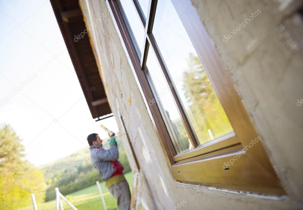 Man applying foam to insulate window