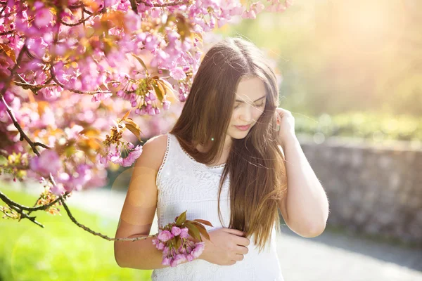 Flicka med rosa blommor — Stockfoto