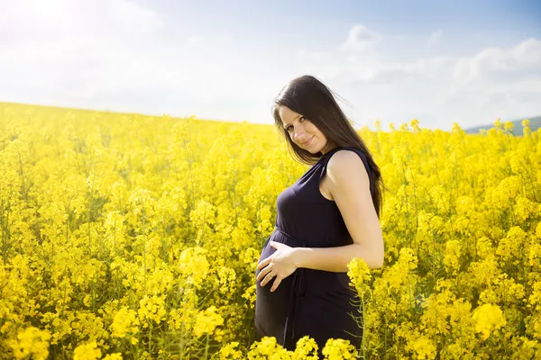 Kobieta w ciąży w pole rzepaku — Zdjęcie stockowe