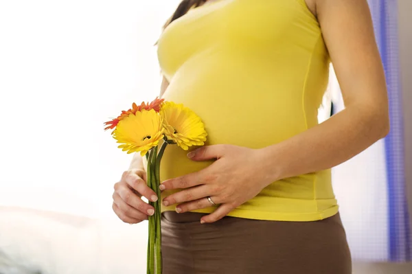 Pregnant woman holding flowers — Stock Photo, Image