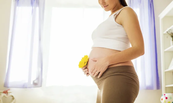 Zwangere vrouw bedrijf bloem — Stockfoto