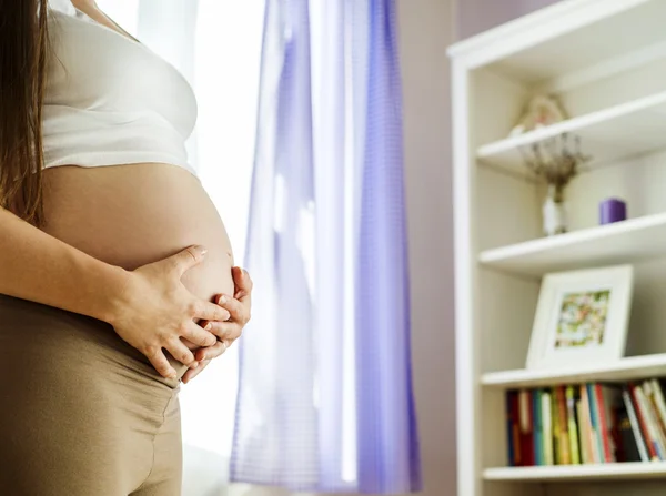 Kvinna med händerna över magen — Stockfoto