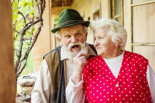 Old couple standing by house — Stock Photo, Image