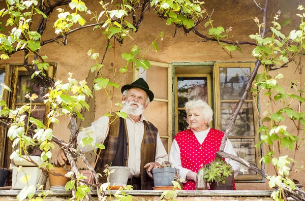 Oude paar staande door huis — Stockfoto