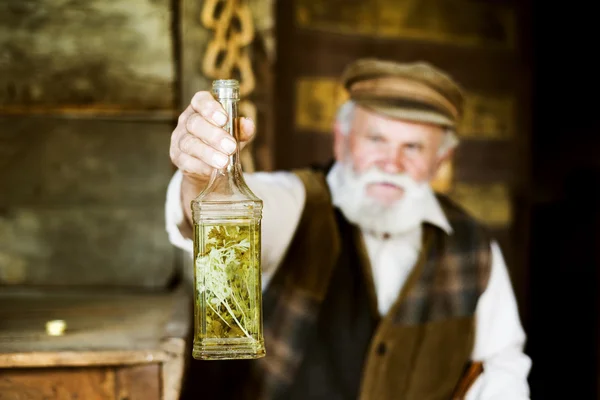 Farmer with bottle of herbal spirit — Stock Photo, Image