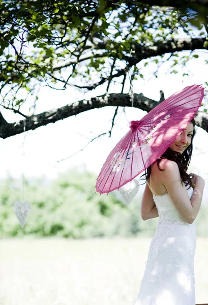 Brud med paraply på ängen — Stockfoto