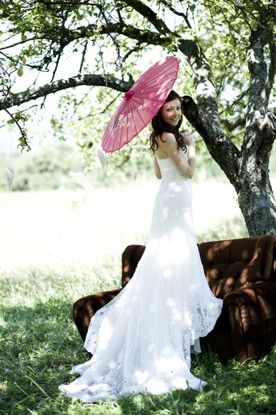 Bride with umbrella at meadow — Stock Photo, Image