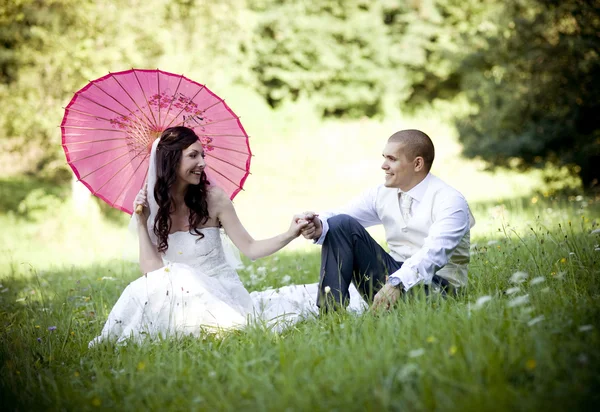 Nevěsta a ženich seděl na trávě — Stock fotografie