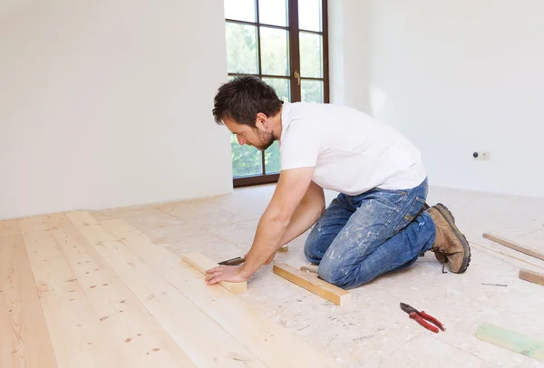 Handyman installing wooden floor — Stock Photo, Image