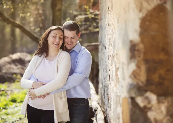 Embarazada pareja abrazándose en la naturaleza — Foto de Stock