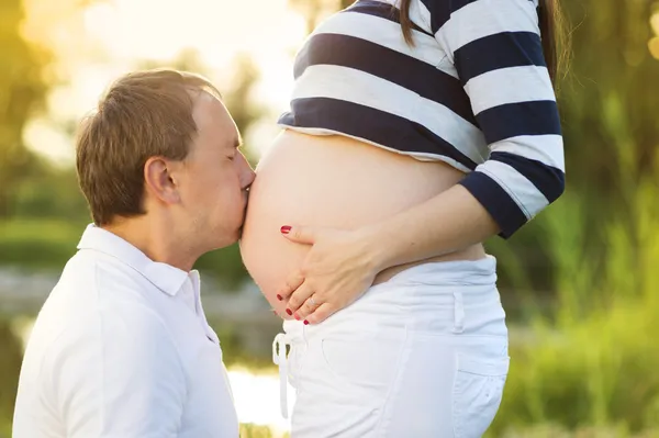 Man kussen zwangere buik — Stockfoto