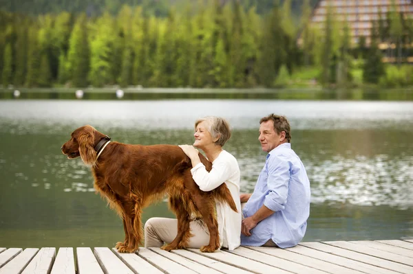 Couple with dog sitting on pier — Stock Photo, Image