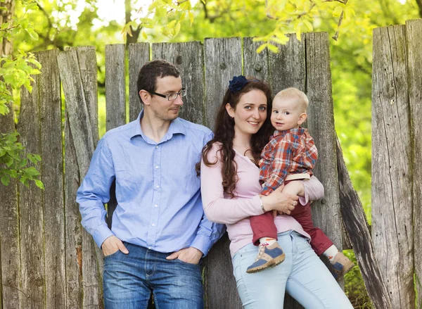 Rodina pózuje v blízkosti dřevěného plotu — Stock fotografie