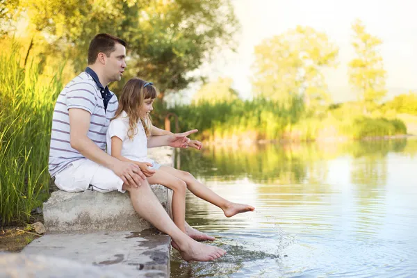 Otec sedí u jezera s dcerou — Stock fotografie