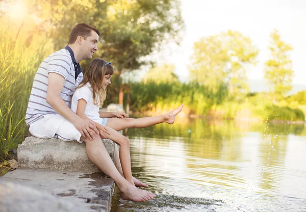 Отец сидит у озера с дочерью — стоковое фото