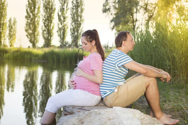 Casal grávida relaxante por lago — Fotografia de Stock